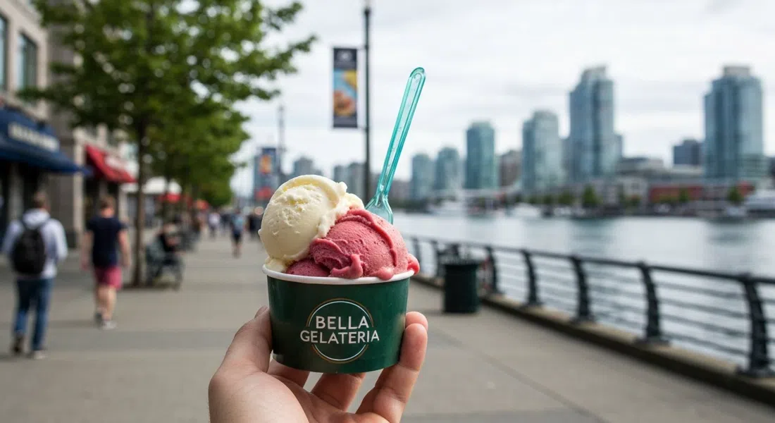 Una bola de gelato artesanal de Bella Gelateria en un vaso, fotografiada a nivel de calle en Coal Harbour con el paseo marítimo suavemente desenfocado detrás