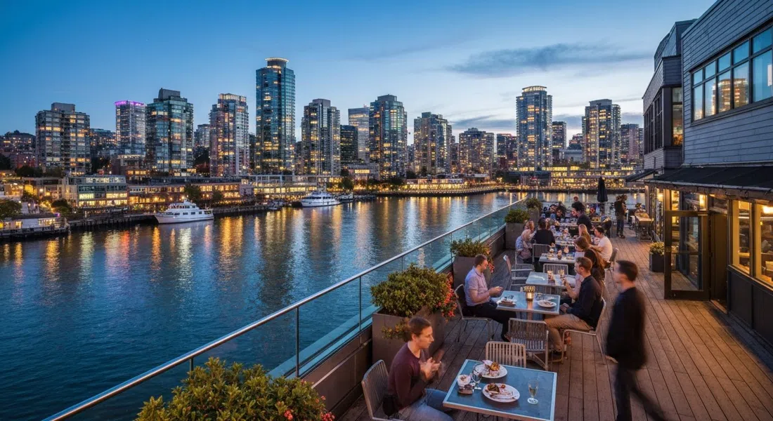 la terraza en la azotea de Sandbar Seafood Restaurant al atardecer, con el agua de False Creek abajo y las torres del centro brillando al otro lado del canal